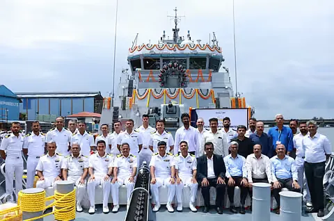 Naval officers, sailors and shipyard staff seated and standing together on the deck of a newly built vessel at a commissioning ceremony