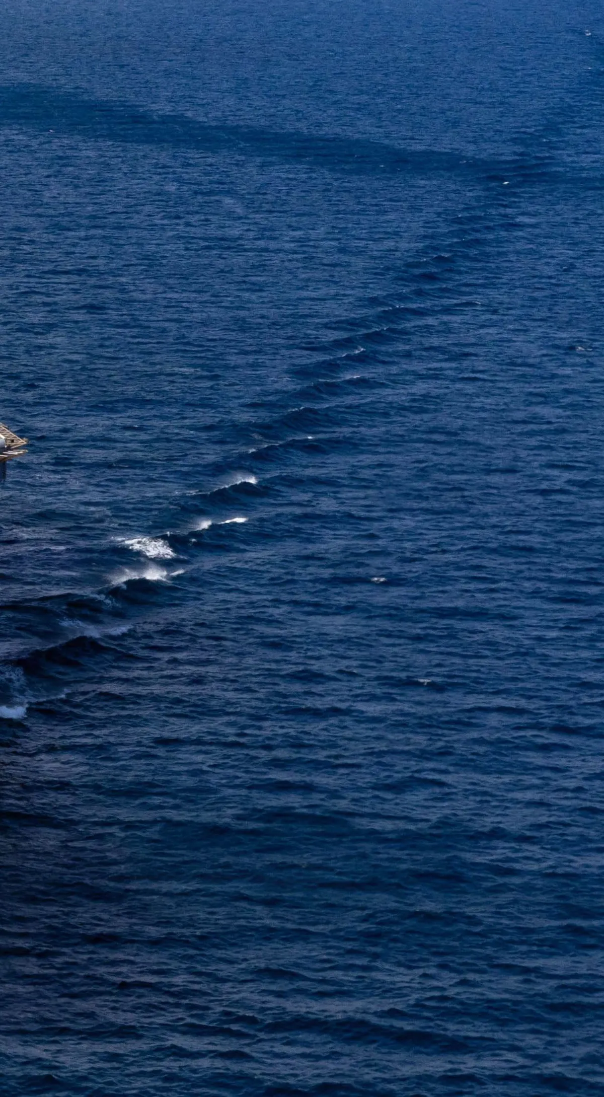 Deep blue open ocean crossed by the white wake lines of passing ships